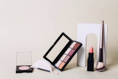 Gölgeli ve kamuflajlı makyaj paletleri. Bej arka plandaki ürünleri uydur