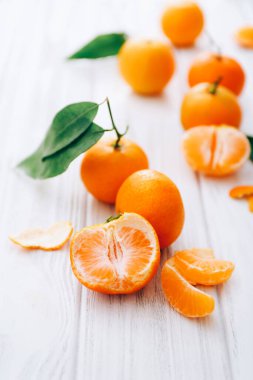 Beyaz ahşap masa üzerinde yaprakları olan taze mandalinalar..