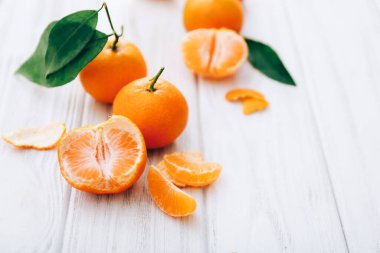 Ahşap masa arkasında yaprakları olan taze mandalinalar.