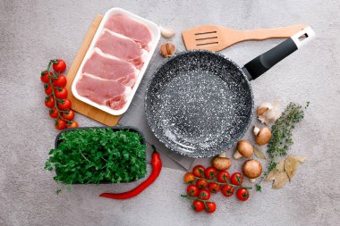 Gri masa zemininde ürünleri olan siyah mermer kızartma tavası, üst manzara.