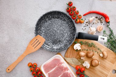 Black marble frying pan with products on grey background, top view