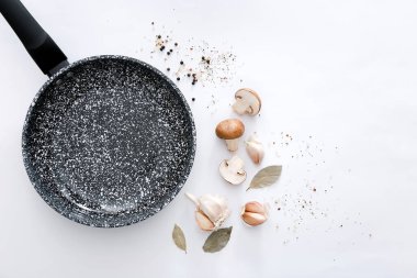 Black marble frying pan with products on light grey background, top view