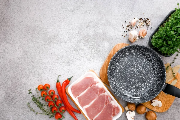 Gri masa zemininde ürünleri olan siyah mermer kızartma tavası, üst manzara.
