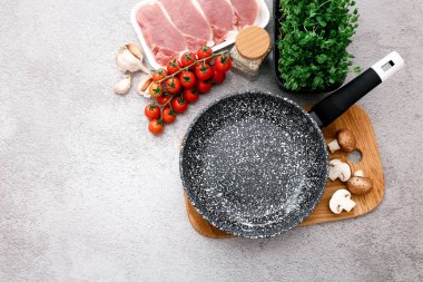 Gri masa zemininde ürünleri olan siyah mermer kızartma tavası, üst manzara.