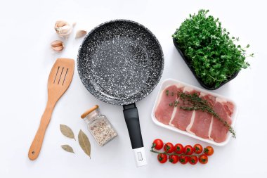 Black marble frying pan with products on grey background, top view