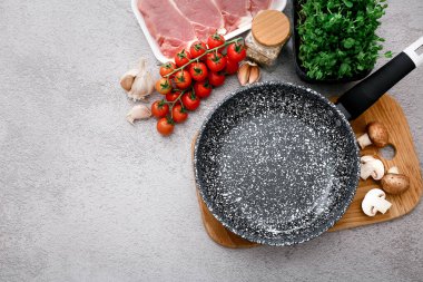 Gri masa zemininde ürünleri olan siyah mermer kızartma tavası, üst manzara.
