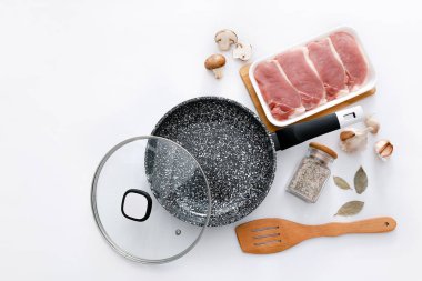 Siyah mermer kızartma tavası, çiğ et ve açık gri arka planda ahşap spatula.