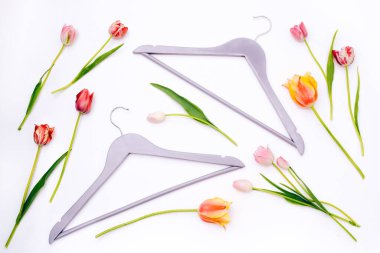 Beyaz arka planda laleleri olan elbise askıları. Düz yatış, üst görünüm