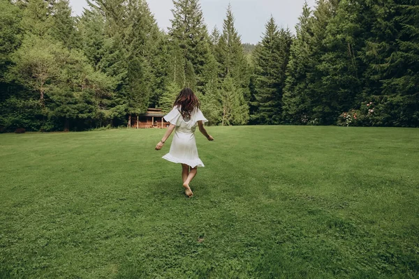 Woman in dress running away towards forest