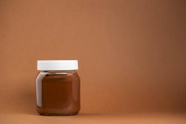 Kahverengi arka planda izole edilmiş çikolata kreması şişesi.