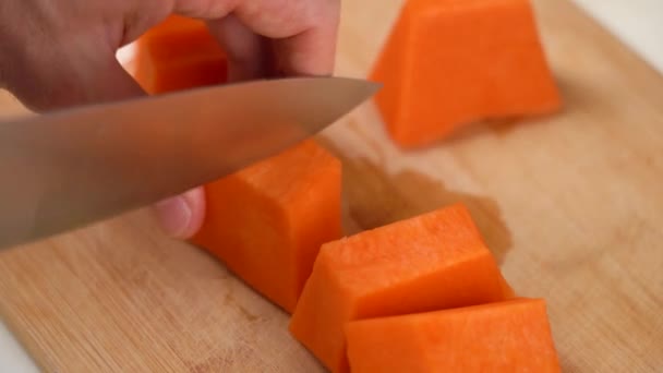 Close-up mannelijke handen voorbereiding pompoen voor het koken met mes op snijplank — Stockvideo