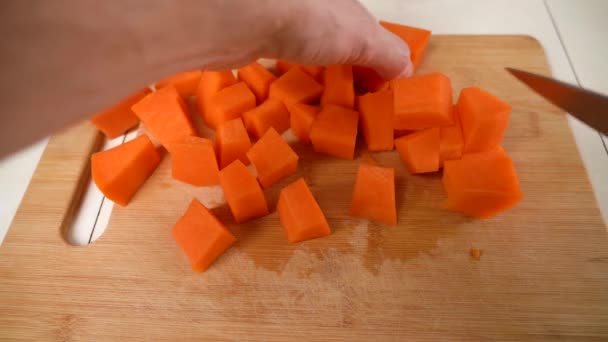 Männliche Hände hacken rohen Kürbis zum Kochen, schneiden ihn mit dem Messer in Würfel. — Stockvideo