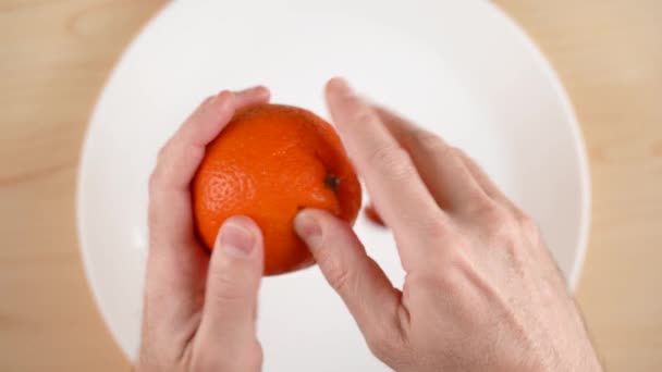 Mens hands peel the peel of mandarins, mandarin slices are piled in a bowl. 4k — Stockvideo