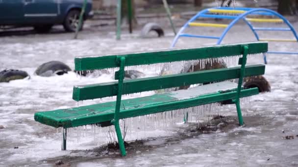 Frozen city bench in ice icicles. Icy city bench after winter natural disaster. — Stock videók