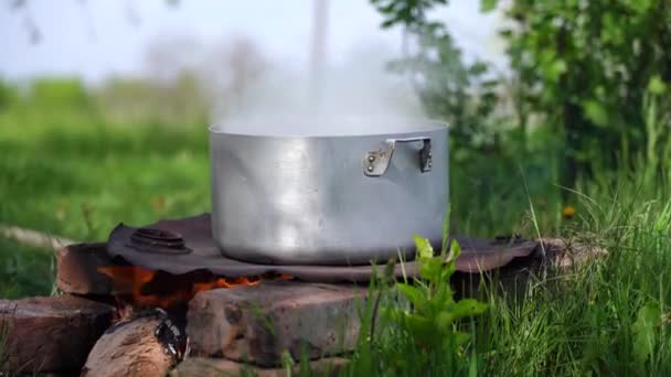 Koken boven een open vuur in pan gaat stoom — Stockvideo