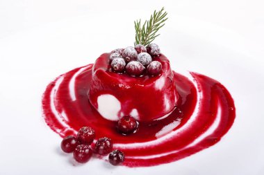 Beyaz arka planda kızılcık soslu sütlü panna-cotta.