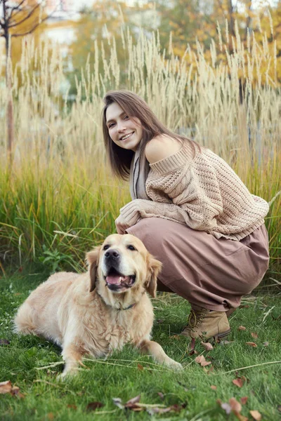 Gadis cantik dengan dua anjing golden retriever di taman — Stok Foto