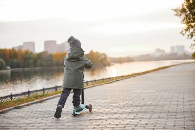 Çocuk set boyunca scooter sürüyor.