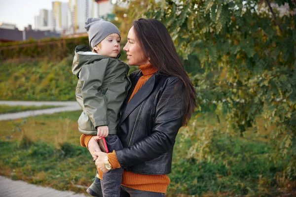 Gyönyörű nő egy babával a karjában. a parkban. — Stock Fotó