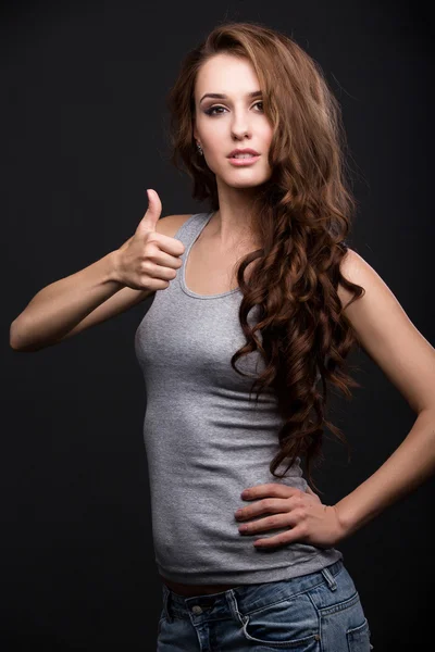 Hermosa chica en gris camisa muestra un pulgar hacia arriba . Imagen de stock