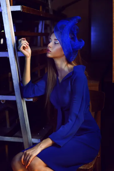 Woman wearing blue dress and blue hat near the ladder — Stock Photo, Image