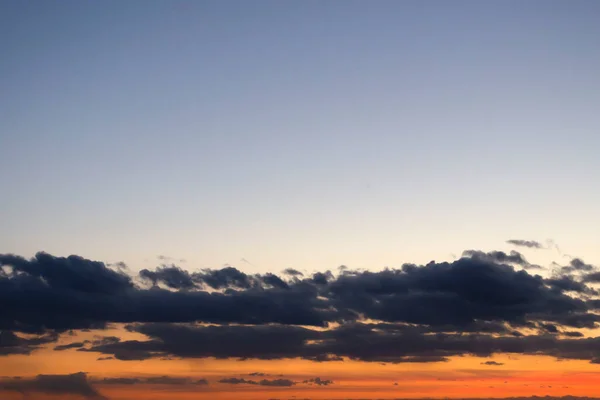 明亮的橙色日落 头顶晴朗的天空 地平线附近乌云密布 — 图库照片