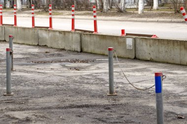 Beton bloklar ve zincirli direklerle çevrili park yeri