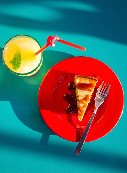 起司蛋糕和柠檬水在蓝色的桌子上 图库照片
