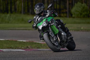 11-05-2021 Riga, Latvia Motorcyclist at sport bike rides by empty asphalt road. green street motorcycle. MotoGP race. Superbikes. Motorbikes racing. Motorcyclist in black suit and black helmet.