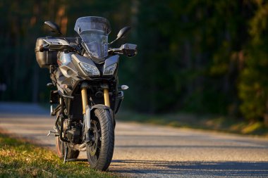 Yolun sağ tarafında ve gün batımında bir motosiklet parkı, odaklanma arkaplanı seçin.