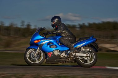 12-09-2022 Riga, Letonyalı adam asfalt yolda motosiklet sürüyor. Spor motosikletinde motosikletçi. Yoldaki motosiklet yarışçısı