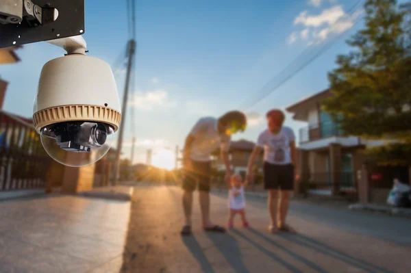 CCTV camera werken met familie in achtergrond van dorp Stockafbeelding