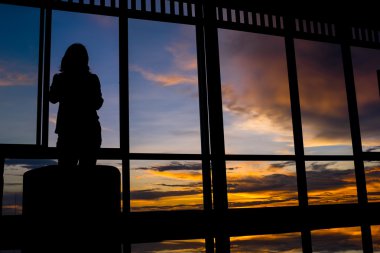 Kız ile alacakaranlık gökyüzü gün batımında cam kenarında ayakta