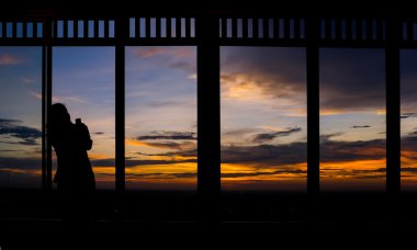 Akıllı telefon alarak fotoğraf alacakaranlık gökyüzü günbatımı kullanan kız