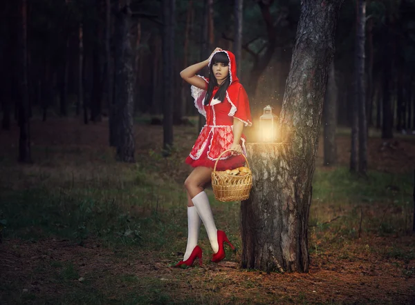 Menina bonita em uma capa de chuva vermelha sozinha na floresta . — Fotografia de Stock