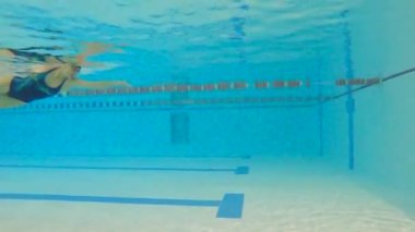 Bir yarışma sırasında sporcu kadın su altında yüzer. Yavaş çekim sporları su altında çekiliyor.