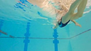 Bir yarışma sırasında sporcu kadın su altında yüzer. Yavaş çekim sporları su altında çekiliyor.