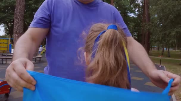 ウクライナの父は娘にウクライナ国旗を結びつけた 彼はウクライナ 祖国を愛することを教えています — ストック動画