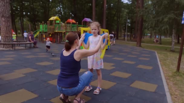 ウクライナ人の母親は娘に故郷を愛するように教える 女の子の肩にウクライナの旗 — ストック動画
