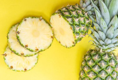 Sarı arka planda doğranmış taze ananas meyveleri.