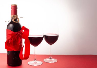 Kırmızı kurdeleli bir şişe kırmızı şarap ve bir kadeh şarap. 14 Şubat Sevgililer Günü