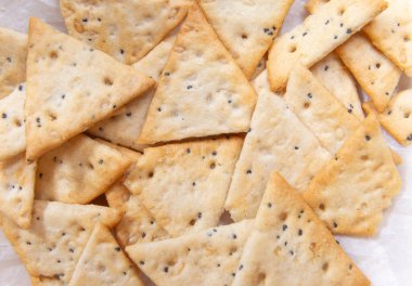 Çıtır üçgen krakerlerin üst görüntüsünü kapat. Tuzlu ve haşhaş tohumlu diyet gevreği.