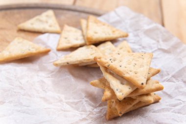 Çıtır üçgen krakerlerin üst görüntüsünü kapat. Tuzlu ve haşhaş tohumlu diyet gevreği.