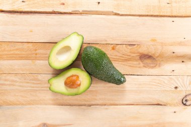 Avokadoyu tahta bir masanın üzerinde bir çukurla kes. en üstteki görünüm