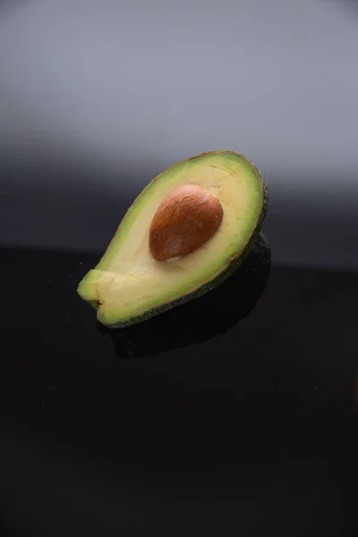 Halv Avokado Med Stift Svart Glas Mörk Avokado Vit Bakgrund — Stockfoto