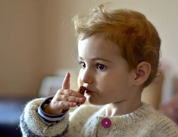 Criança comendo um lanche dentro de casa . — Fotografia de Stock