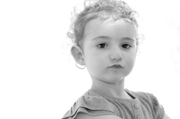 Young child, girl, toddler looking directly at camera with a moody expression. Could also be sad or angry or tantrum. In monochrome. Stock Image