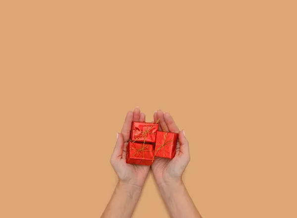 Las manos sostienen una caja de regalo hecha de papel rojo. — Foto de Stock