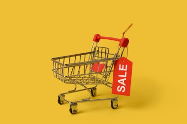 Çevrimiçi alışveriş için boş mini alışveriş arabası. Sarı arka planda.