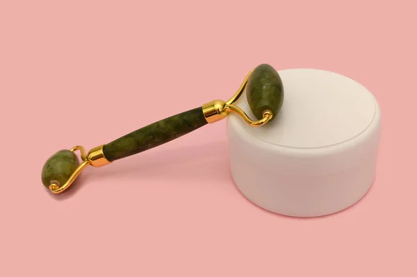 Cosmetic roller for the face, white container on a pink background. — Zdjęcie stockowe